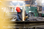 Welder using welding torch in steel factory
