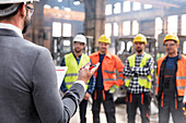 Steel workers listening to manager in meeting