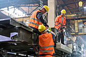 Steel workers fastening crane hook