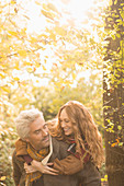 Affectionate couple piggybacking in autumn woods