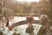Couple talking soaking in hot tub with champagne