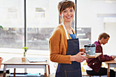 Portrait female cafe owner serving coffee on tray