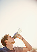 Thirsty male runner drinking water