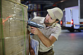 Truck driver worker scanning pallet of boxes