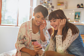 Young women friends sharing headphones