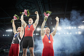 Male gymnasts cheering on winners podium