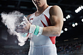Male gymnast applying chalk powder to hands