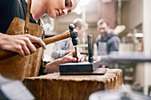Jeweller using hammer in workshop