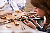 Female jeweller using equipment in workshop