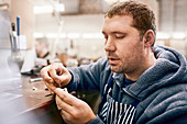 Focused male jeweller making jewellery in workshop