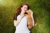 Young woman cuddling affectionate dog in grass