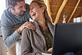 Happy couple laughing and using laptop