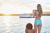 Young woman in bikini photographing houseboat