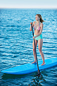Young woman in bikini paddleboarding