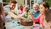 Family reaching for candy on birthday cake