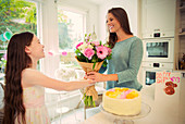 Daughter giving flower bouquet to mother