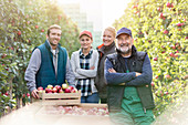 Portrait smiling farmers harvesting apples