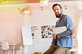 Portrait confident male designer holding laptop