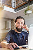 Portrait confident male designer working at laptop