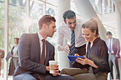 Business people with coffee using tablet, talking