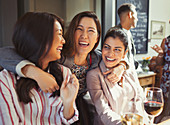 Women friends hugging and drinking at bar
