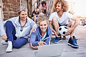 Friends with soccer ball hanging out using laptop