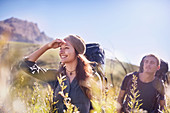 Smiling couple with backpacks hiking in field