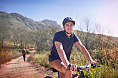 Portrait young man mountain biking on remote trail
