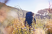 Young man with backpack hiking in field