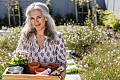 Portrait mature woman carrying gardening tray