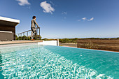 Businessman standing on patio with infinity pool