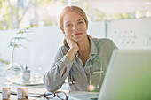 Portrait confident female doctor working at laptop