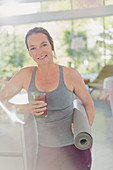 Portrait mature woman with yoga mat drinking juice