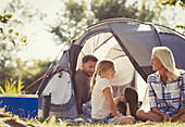 Family talking and relaxing outside tent