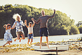 Exuberant family jumping on lake dock
