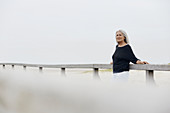 Confident senior woman leaning on beach railing
