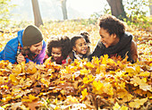 Playful young family laying in autumn leaves