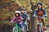 Playful young family bike riding in autumn park