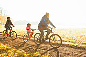 Young family bike riding on path in autumn park