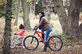 Mother and daughter bike riding in autumn woods