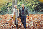 Senior couple walking in autumn leaves in park