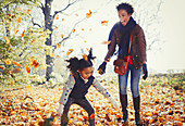Playful mother and daughter throwing leaves