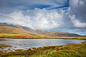 Clouds and rainbow beyond lake, Hebrides, Scotland