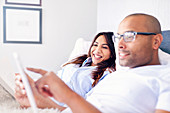 Smiling couple using tablet on bed