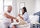 Smiling couple drinking coffee in bed