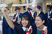 College women in cap and gown taking selfie