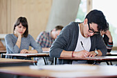 Male college student taking test at desk