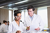 College students in lab coats discussing notes