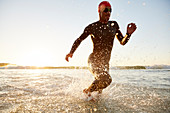 Male triathlete swimmer running from ocean