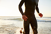 Male triathlete swimmer running out of ocean surf